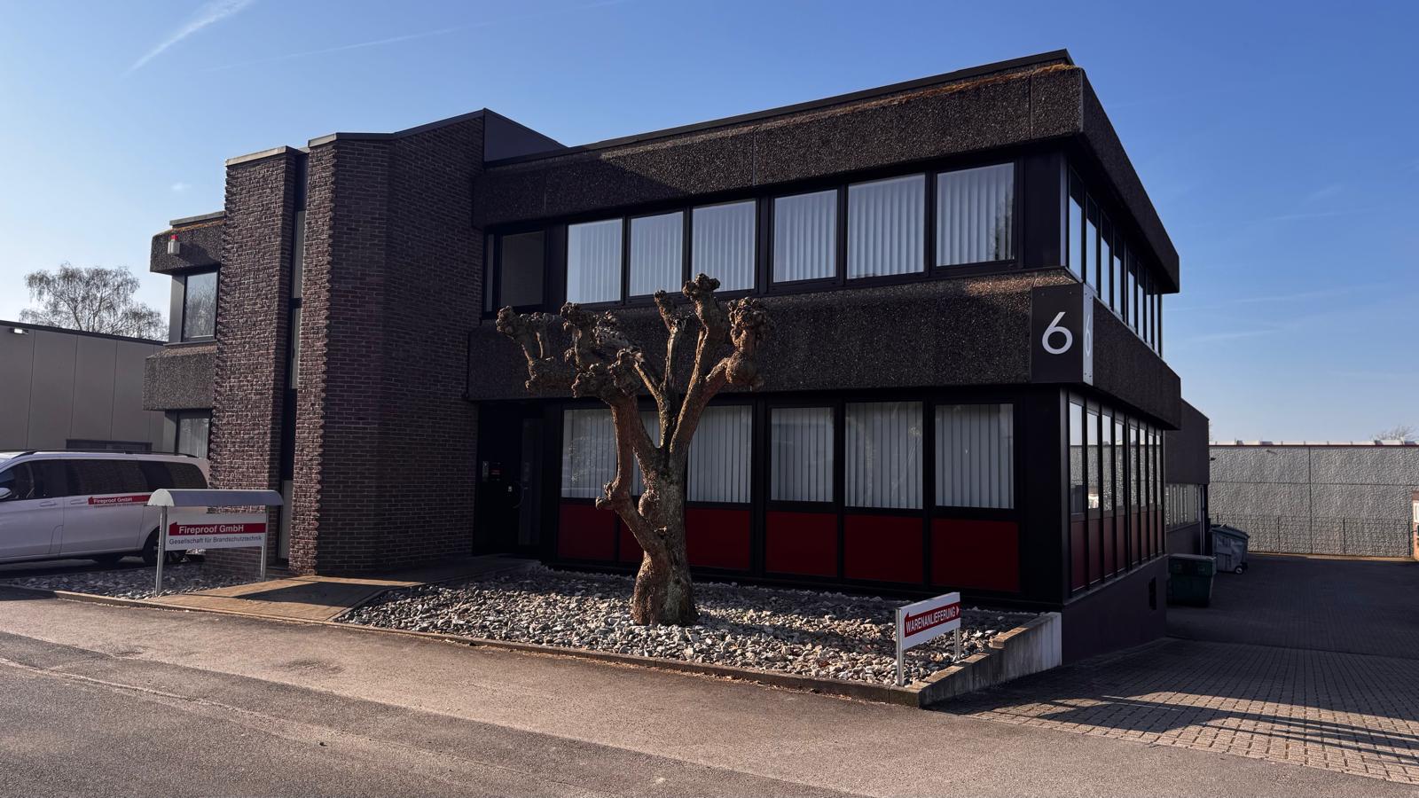 Ein modernes zweistöckiges Bürogebäude mit dunkler Fassade und rotem Akzent